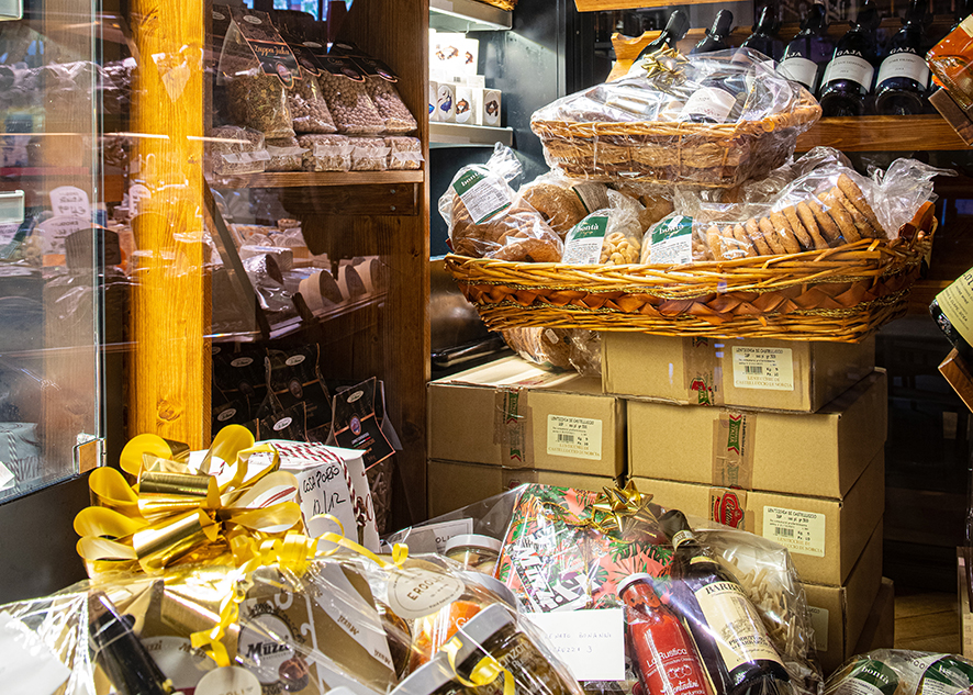 Christmas baskets full of luxury delicatessen in wine bar store bottles on shelf in background